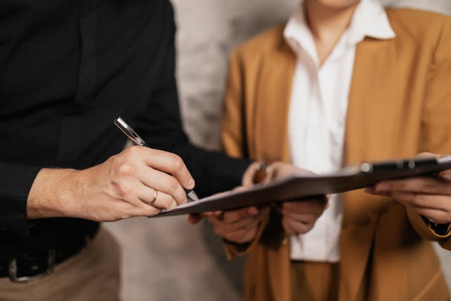 A member of a property management team reviewing a contract on a clipboard with a tenant.